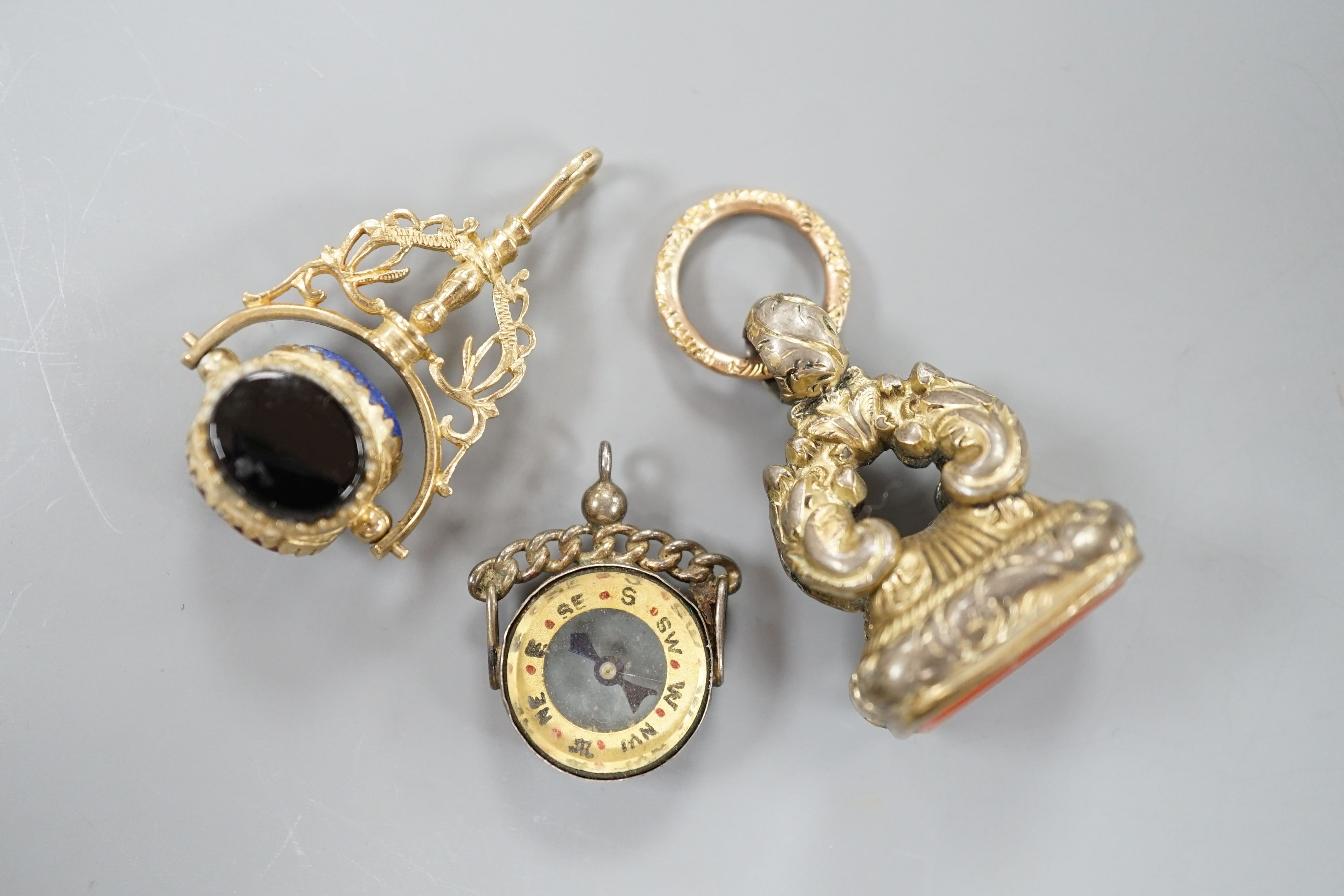 A modern 9ct gold and carnelian set swivelling fob seal, 40mm, a Victorian gold plated and carnelian set fob seal and a white metal mounted (stamped silver) compass fob.